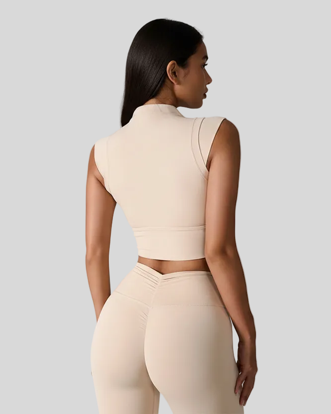 Woman wearing a tan sleeveless top and leggings against a light gray background