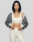 Woman wearing black striped cropped cardigan open over neutral activewear set