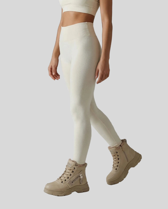 Model wearing cream leggings and khaki TerrainForm boots on a gray background