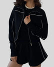 Mid body view of Athlesi black TrackEase jacket and shorts set