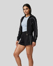 Side view of model wearing Athlesi black TrackEase jacket and shorts set