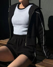 Model seated wearing Athlesi black TrackEase jacket and shorts set