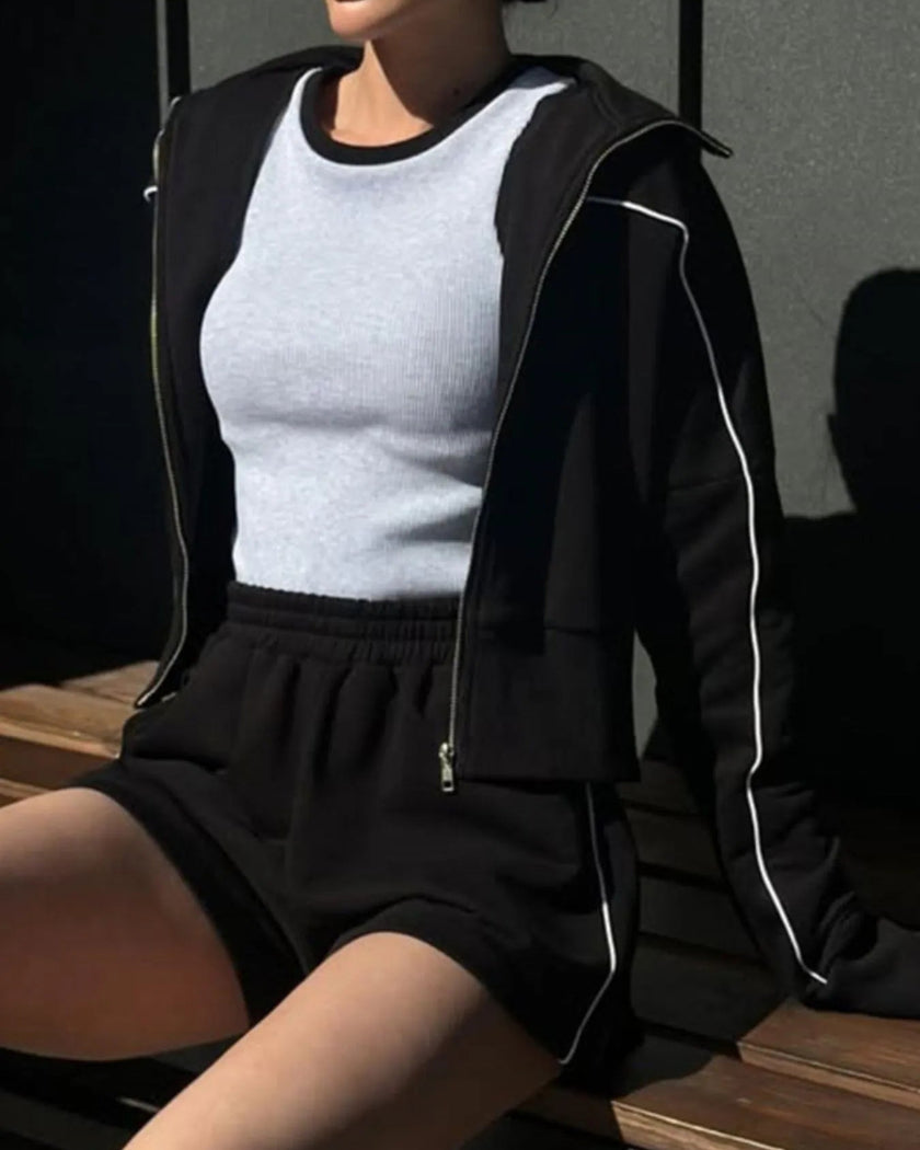 Model seated wearing Athlesi black TrackEase jacket and shorts set