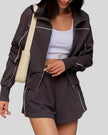 Mid body view of Athlesi brown TrackEase jacket and shorts set