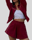 Mid body view of Athlesi burgundy TrackEase jacket and shorts set