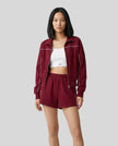 Mid body view of Model wearing Athlesi burgundy TrackEase jacket and shorts set