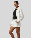 Side view of model wearing Athlesi ivory TrackEase jacket and shorts set