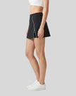 Side view of a woman wearing the Athlesi TrackLine A-Line Skirt in black
