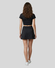 Full body back view of the Athlesi TrackLine A-Line Skirt in black styled with the matching TrackLine Lapel Crop Top