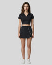 Full body front view of the Athlesi TrackLine A-Line Skirt in black styled with the matching TrackLine Lapel Crop Top
