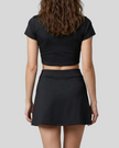 Mid body back view of the Athlesi TrackLine A-Line Skirt in black styled with the matching TrackLine Lapel Crop Top