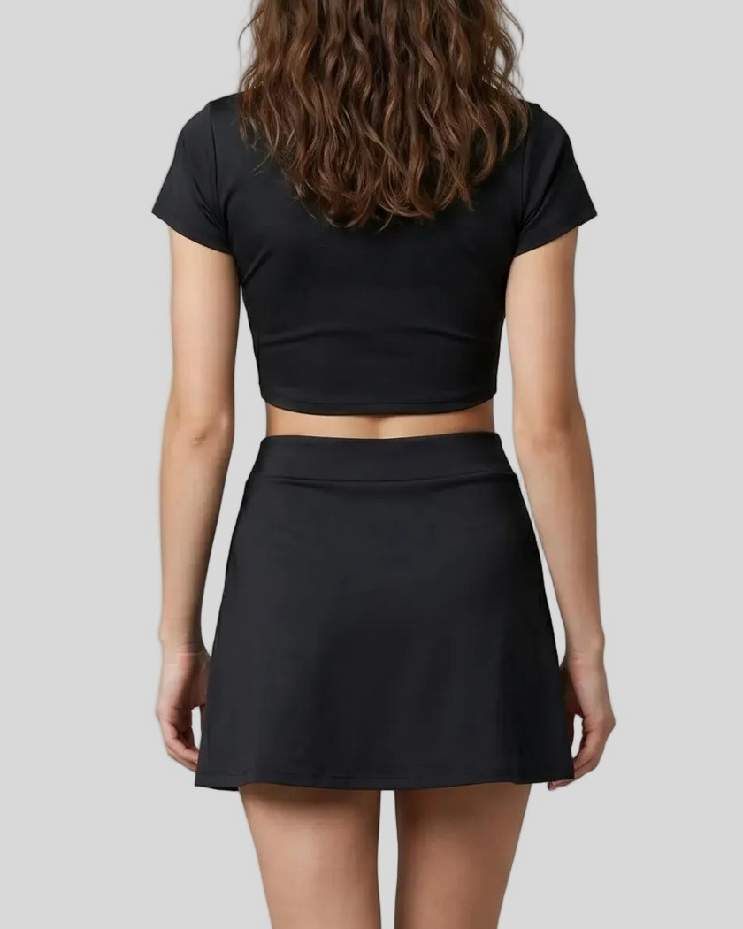 Mid body back view of the Athlesi TrackLine A-Line Skirt in black styled with the matching TrackLine Lapel Crop Top