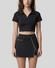 Mid body front view of the Athlesi TrackLine A-Line Skirt in black styled with the matching TrackLine Lapel Crop Top