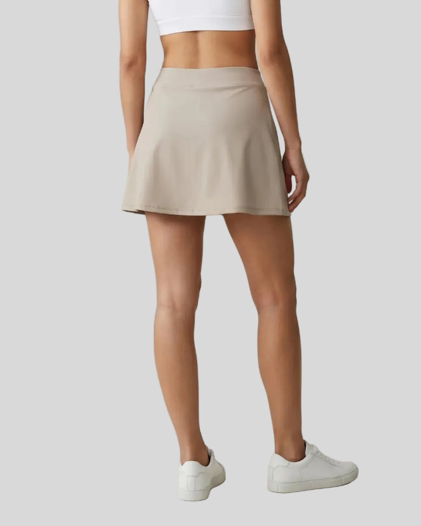 Lower body back view of a woman wearing the Athlesi TrackLine A-Line Skirt in light coffee