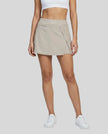 Lower body front view of a woman wearing the Athlesi TrackLine A-Line Skirt in light coffee