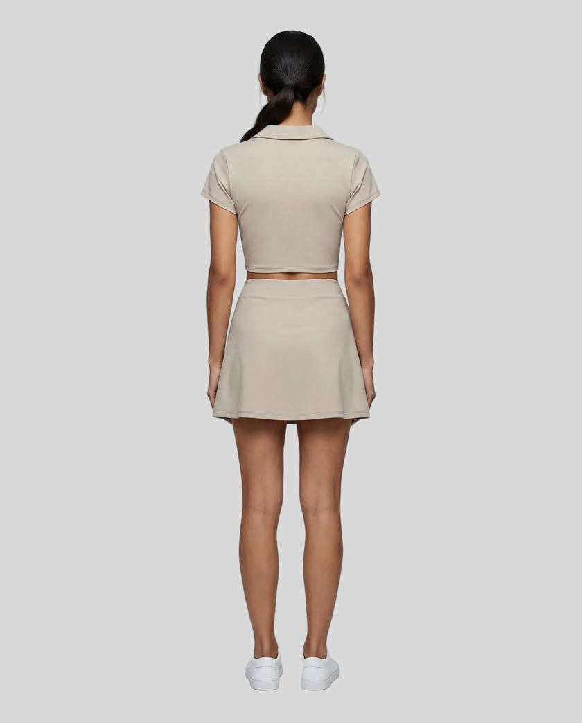 Full body back view of the Athlesi TrackLine A-Line Skirt in light coffee styled with the matching TrackLine Lapel Crop Top