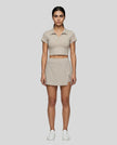Full body front view of the Athlesi TrackLine A-Line Skirt in light coffee styled with the matching TrackLine Lapel Crop Top