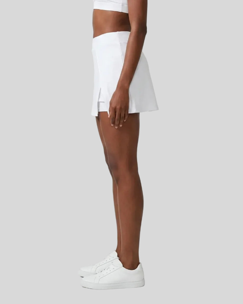 Side view of a woman wearing the Athlesi TrackLine A-Line Skirt in white