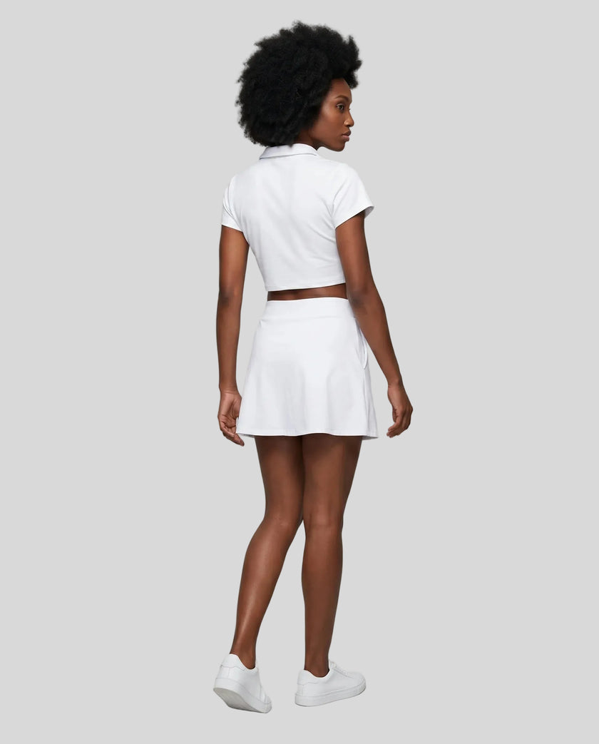 Full body back view of the Athlesi TrackLine A-Line Skirt in white styled with the matching TrackLine Lapel Crop Top