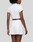 Mid body back view of the Athlesi TrackLine A-Line Skirt in white styled with the matching TrackLine Lapel Crop Top