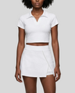 Mid body front view of the Athlesi TrackLine A-Line Skirt in white styled with the matching TrackLine Lapel Crop Top