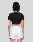 Woman wearing the TrackLine Baseball Jersey in Black from the back showing its cropped silhouette and contrast sleeve trim