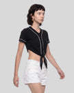Woman wearing the TrackLine Baseball Jersey in Black from a side angle showing the contrast piping and fitted shape.