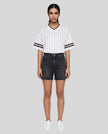 Woman wearing the TrackLine Baseball Striped Tee in White from a front angle showing the oversized silhouette and striped sleeve details.