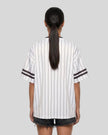 Woman wearing the TrackLine Baseball Striped Tee in White from the back showing its relaxed fit, drop shoulders, and vertical pinstripes.