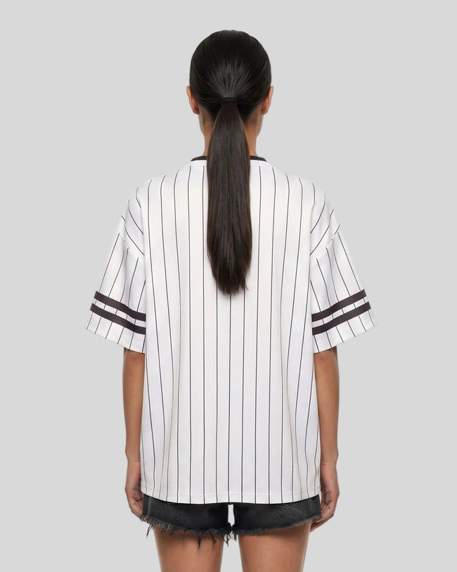 Woman wearing the TrackLine Baseball Striped Tee in White from the back showing its relaxed fit, drop shoulders, and vertical pinstripes.