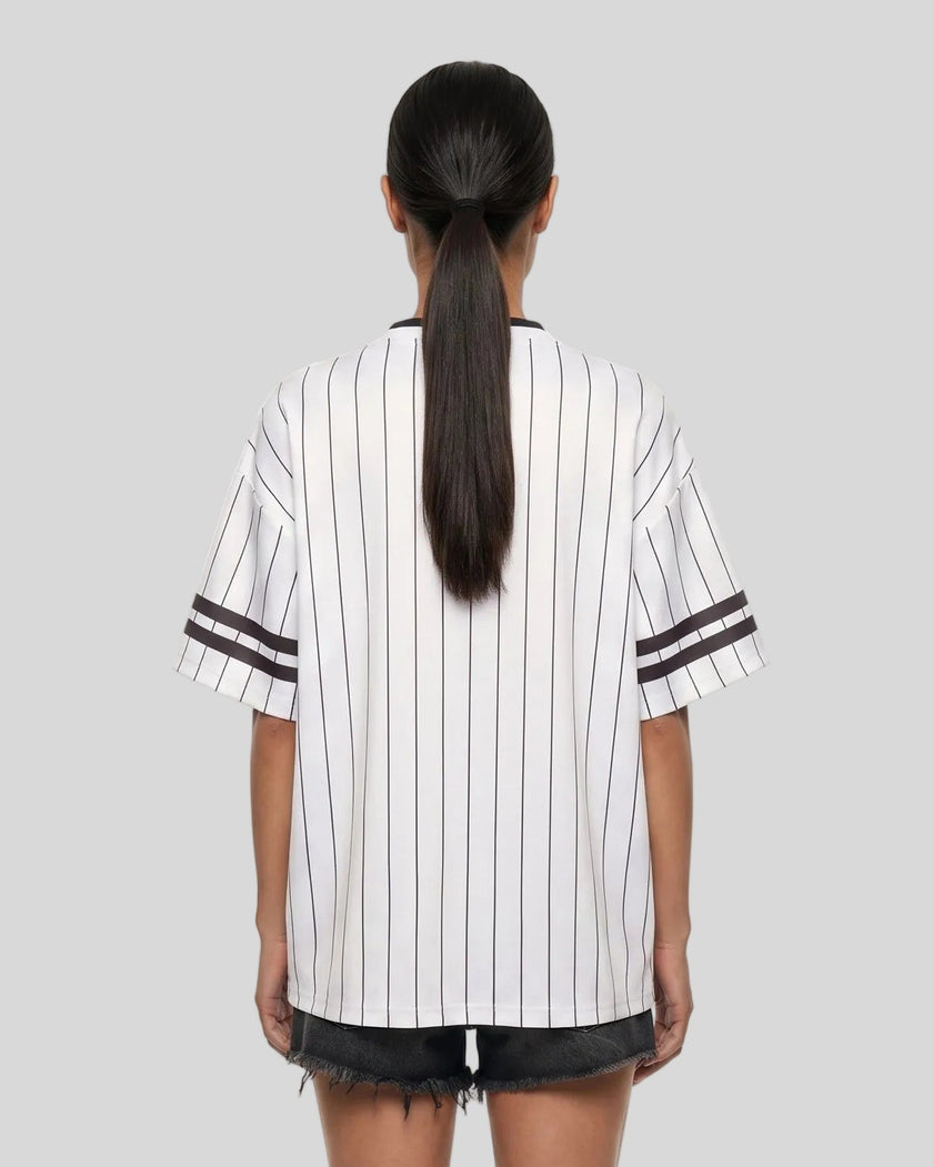 Woman wearing the TrackLine Baseball Striped Tee in White from the back showing its relaxed fit, drop shoulders, and vertical pinstripes.