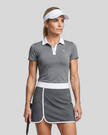 Woman wearing Athlesi TrackLine Color Block Skort in Dark Gray mid-body front view showing contrast waistband and overlapping hem