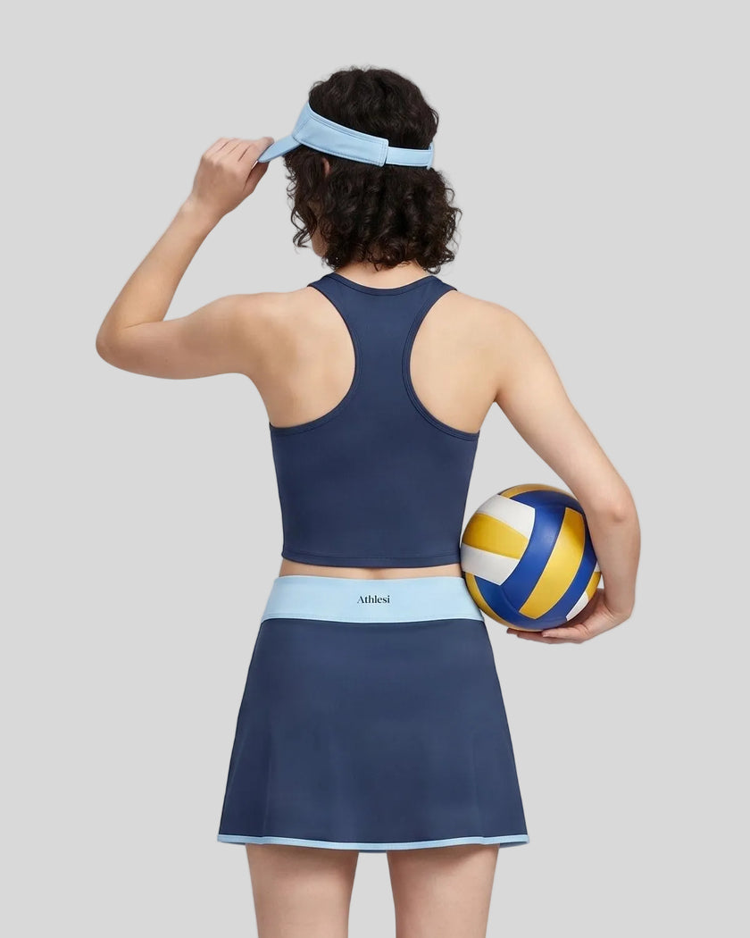 Woman wearing Athlesi TrackLine Color Block Skort in Navy Blue mid-body back view showing contrast waistband and skirt silhouette