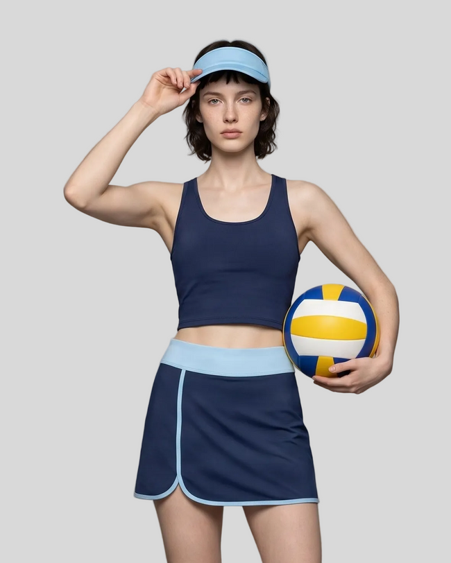 Woman wearing Athlesi TrackLine Color Block Skort in Navy Blue mid-body front view showing contrast waistband and overlapping hem