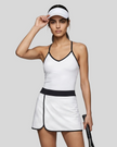 Woman wearing Athlesi TrackLine Color Block Skort in White mid-body front view showing contrast waistband and overlapping hem