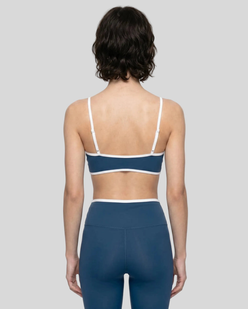 Back view of model wearing the Athlesi TrackLine Color Block Sports Bra in blue and white
