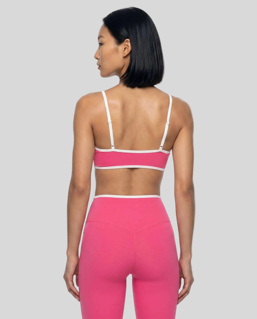 Back view of model wearing the Athlesi TrackLine Color Block Sports Bra in pink and white
