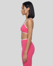 Side profile of model wearing the Athlesi TrackLine Color Block Sports Bra in pink and white