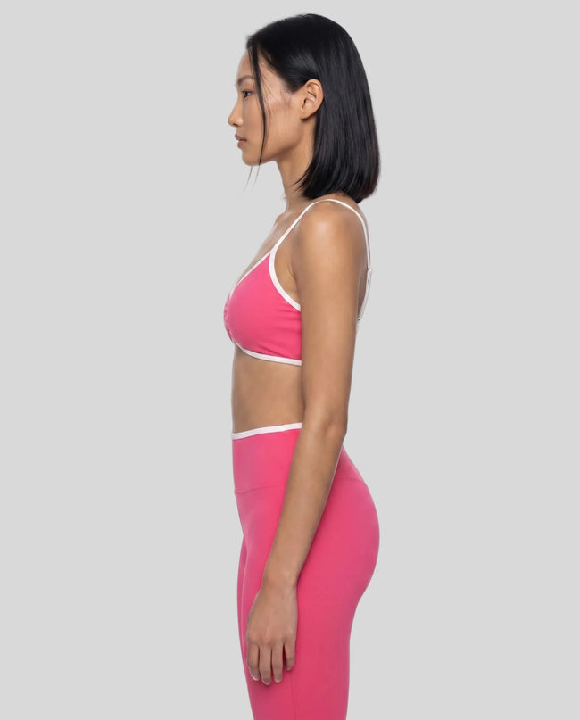 Side profile of model wearing the Athlesi TrackLine Color Block Sports Bra in pink and white