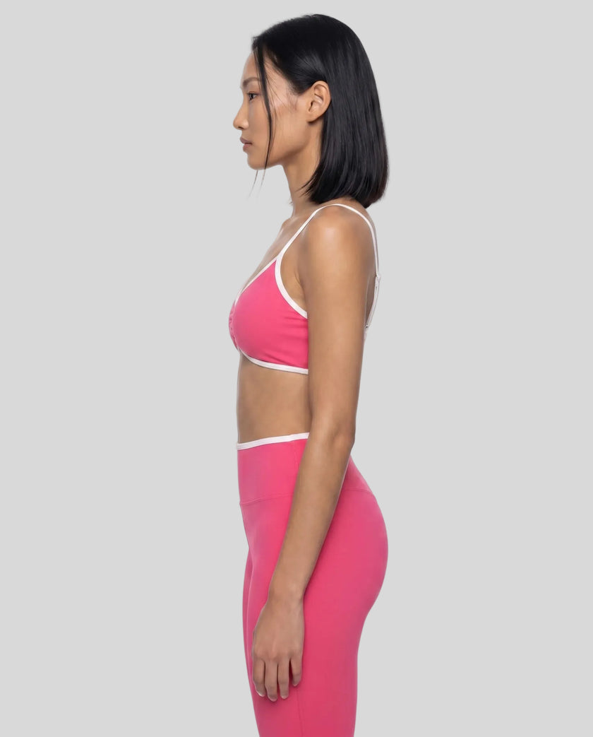 Side profile of model wearing the Athlesi TrackLine Color Block Sports Bra in pink and white