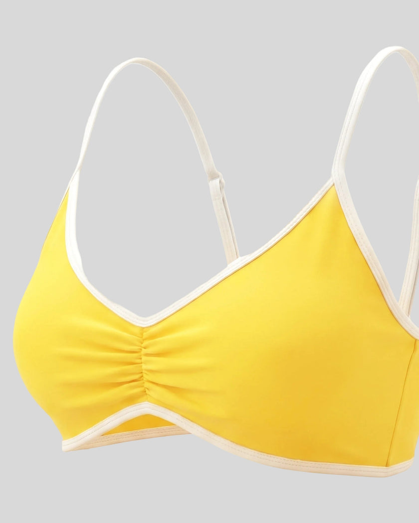 Angled closeup of the Athlesi TrackLine Color Block Sports Bra in yellow and white