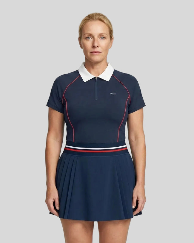 Female model wearing the TrackLine Court Polo in Navy Blue paired with Trackline Rally Skirt in Navy Blue viewed from the front.