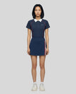 Female model wearing the TrackLine Court Polo in Navy Blue paired with Trackline Rally Slit Skirt in Navy Blue, viewed full body from the front
