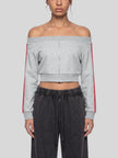 A model wearing a flower gray TrackLine Edge Kacket with red side stripes, paired with dark gray sweatpants.