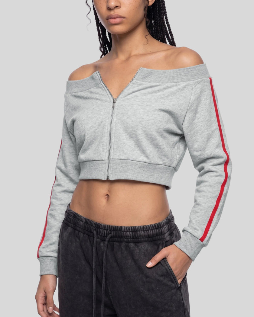 A woman wearing a flower gray off-the-shoulder cropped zip-up TrackLine Edge Jacket with red side stripes and dark gray sweatpants.
