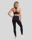 Model wearing the Athlesi TrackLine Edge Leggings in black with high-rise waist and V-shaped back seam, back view