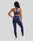 Model wearing the Athlesi TrackLine Edge Leggings in navy blue with high-rise waist and V-shaped back seam, back view
