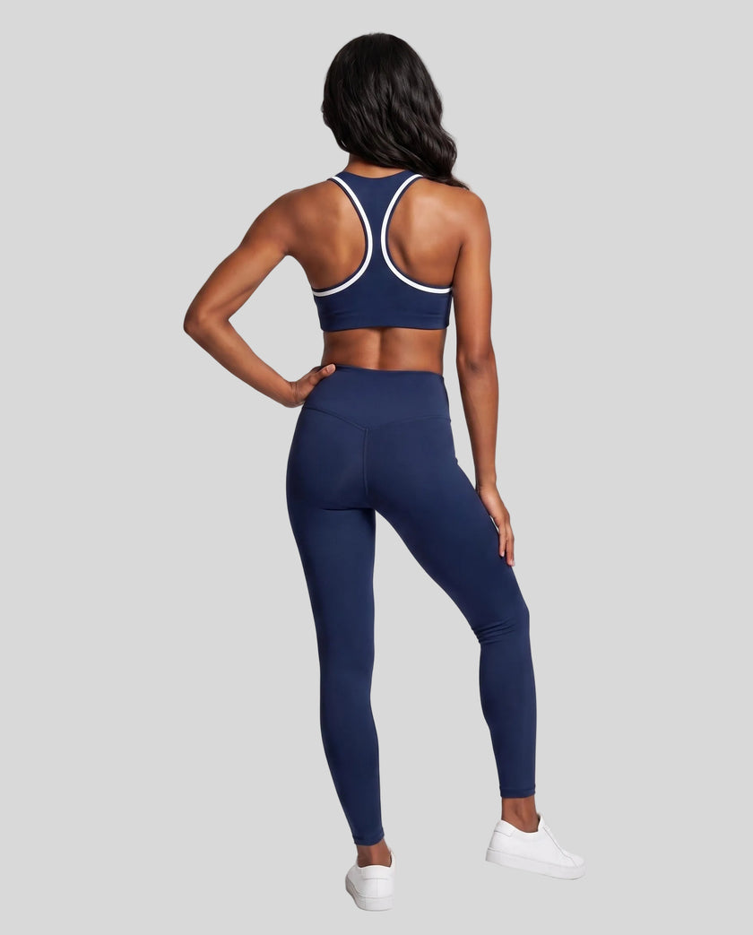 Model wearing the Athlesi TrackLine Edge Leggings in navy blue with high-rise waist and V-shaped back seam, back view