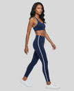 Model wearing the Athlesi TrackLine Edge Leggings in navy blue with white side stripes from a side angle
