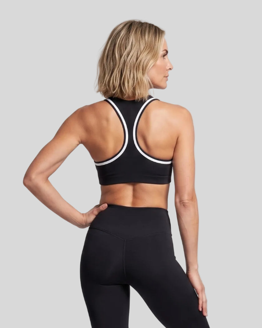 Model wearing the Athlesi TrackLine Edge Sports Bra in black with white contrast trim and racerback design, back view